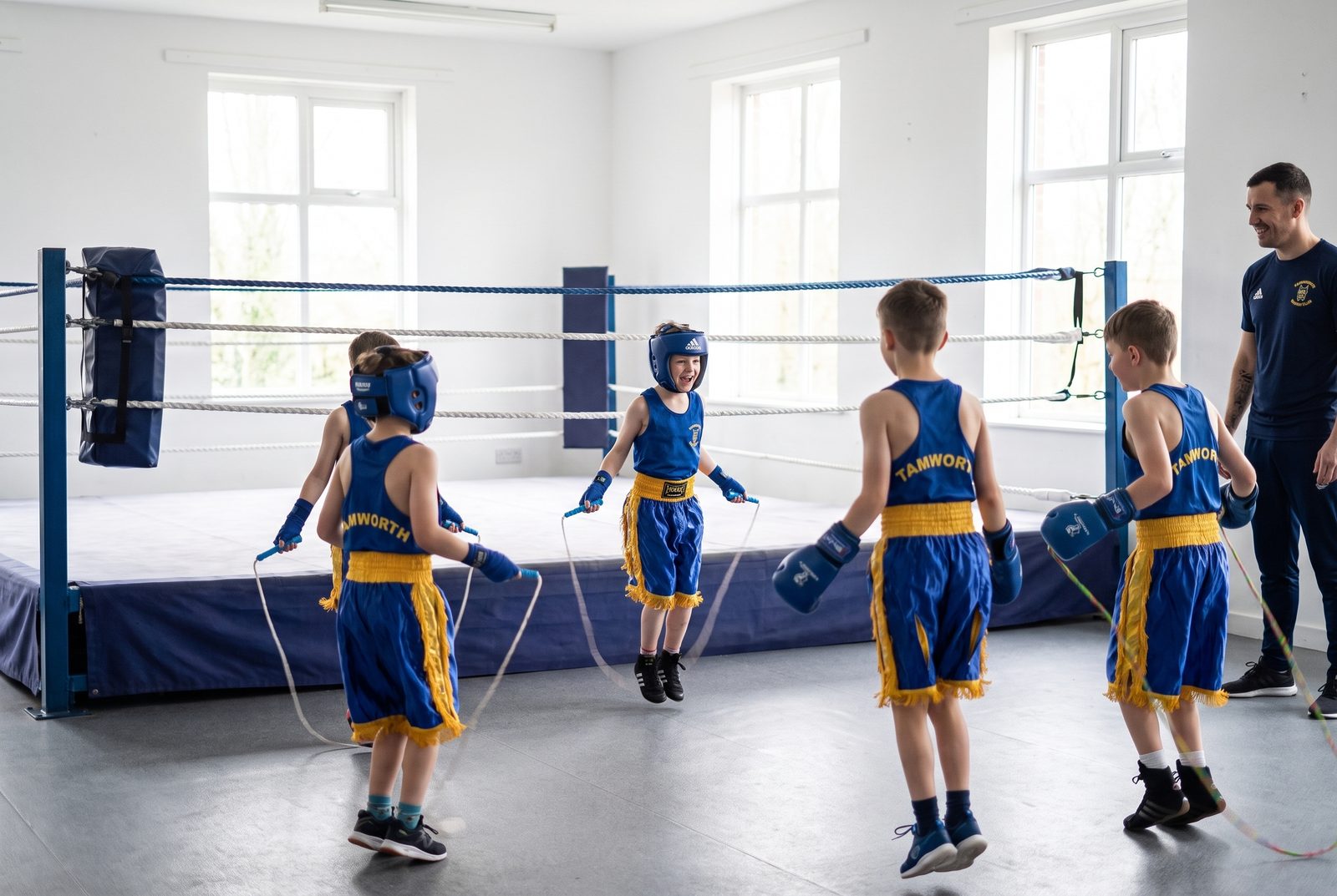 Children in a minors session skipping on the gym floor while a coach watches