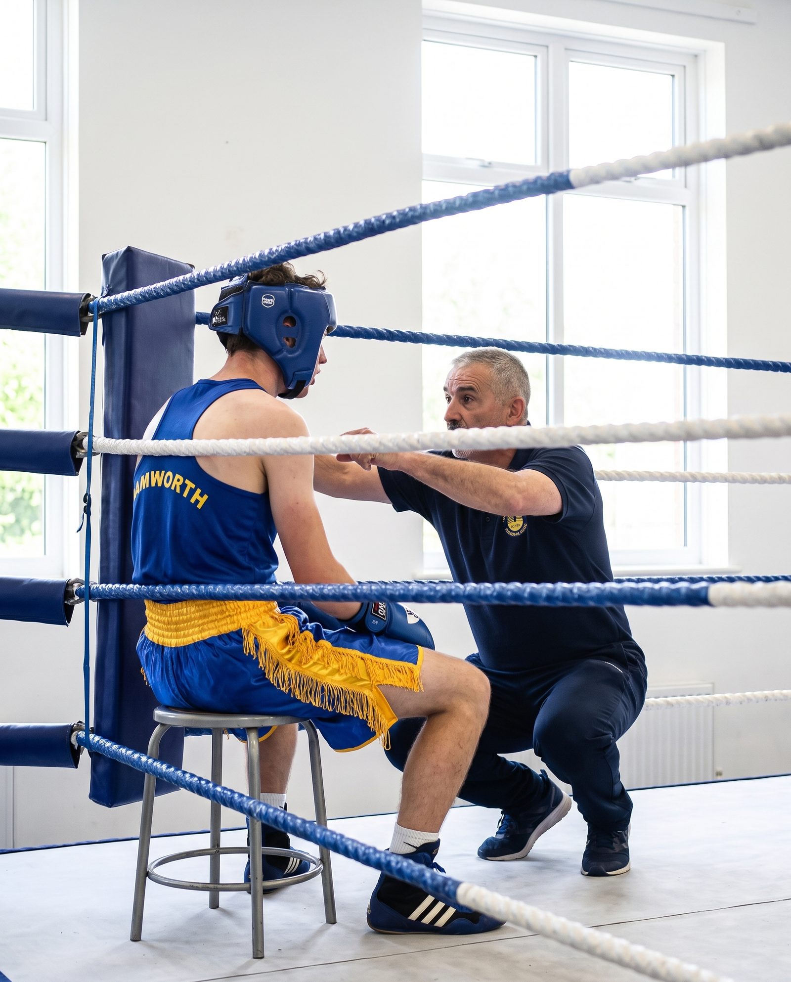 A coach talking to a young boxer in the corner between rounds