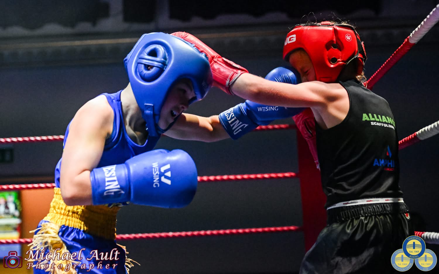Two juniors in headguards boxing at a home show