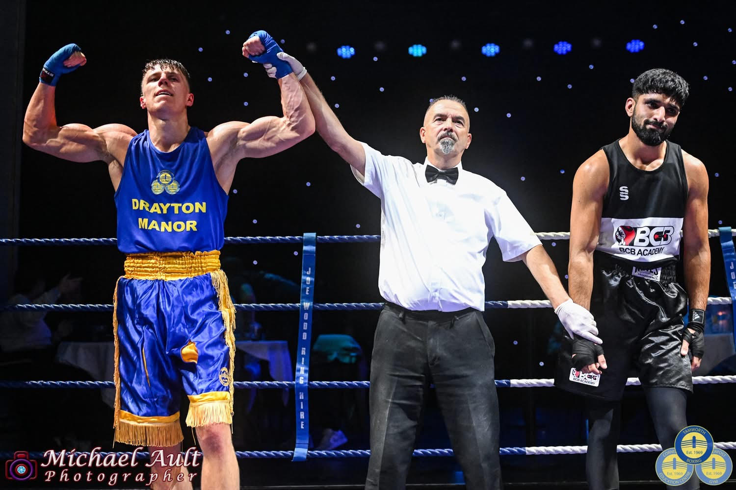 A Tamworth boxer in a Drayton Manor vest has his hand raised by the referee
